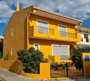un edificio giallo con una recinzione di fronte di Ria Formosa Pineview a Faro