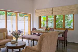 a living room with a table and chairs and windows at Villa Eden 3BHK in Assagao