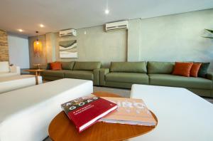 a living room with a couch and a book on a table at Wave Suítes Hotel & Lounge bar in Maceió