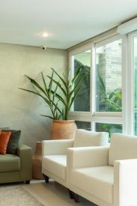 a living room with white chairs and a potted plant at Wave Suítes Hotel & Lounge bar in Maceió