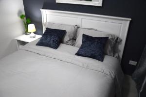 Una cama blanca con dos almohadas azules. en Jazz Makati Luxury Apartment en Manila