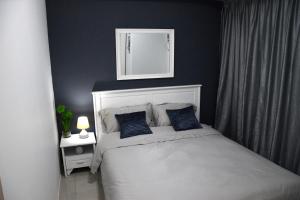 Jazz Makati Luxury Apartment في مانيلا: غرفة نوم مع سرير والجدران الزرقاء ومرآة