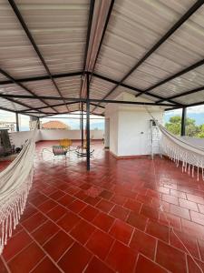 a large room with red tile floor and hammocks at Habitaciones Stonehaven Ruitoque in Piedecuesta