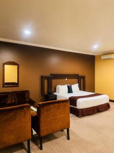 a hotel room with a bed and a chair at Gmasters Boutique Hotel in Kigali