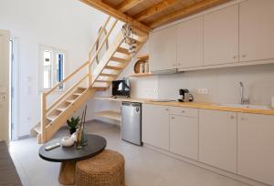 a kitchen with white cabinets and a spiral staircase at Studio Anna in Vathi