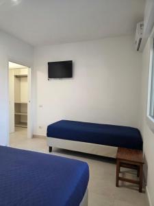 a bedroom with two beds and a tv on the wall at Villetta Lu Sule in Porto Cesareo