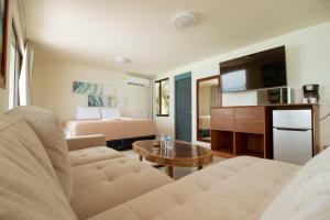 a living room with a couch and a bed and a television at Charly Beach Hotel in Isla Mujeres