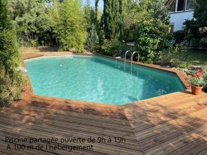 a swimming pool in a yard with a wooden deck at Maison avec accès piscine partagée in Colmar
