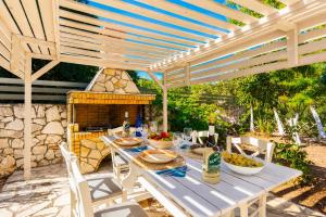 a picnic table under a wooden pergola with food on it at Villa Canova in Mesovoúnia
