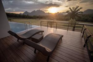 a wooden deck with two chairs and a swimming pool at Belong Jin The Dam Resort in Ban Pha Saeng Lang