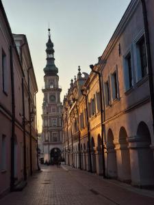 an empty street with a clock tower in the distance at Przy Głównej in Zamość