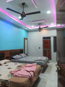 a room with two beds and a ceiling with pink lights at Hotel sawariya in Godarpura