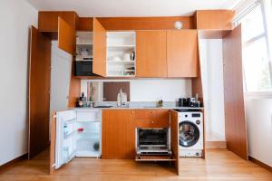 a kitchen with wooden cabinets and a washer and dryer at Studio Design Paris 20 min RER A in Nogent-sur-Marne