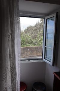 a window with a white curtain and a view at Casa das Brisas Matinais in Conceição