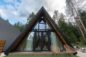 a house with a triangular roof with two chairs at Durmitor forest lodge in Žabljak