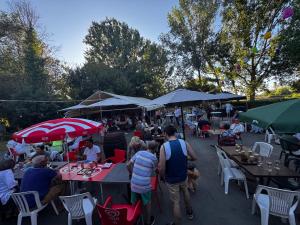 a group of people sitting at tables with umbrellas at Camping les sablons in Vergeroux