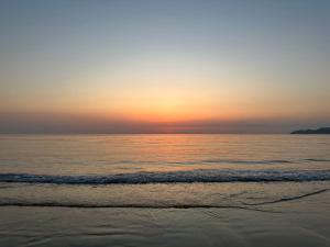 a person walking on the beach at sunset at Secret Beach House MOKU in Fukutsu