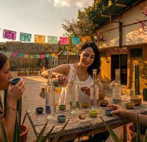 a woman sitting at a table with bottles on it at Casa Centro Historico Hostel in Oaxaca City