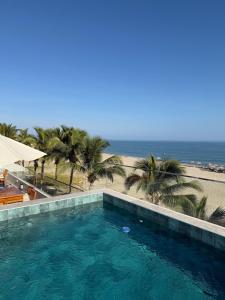 a swimming pool next to a beach with palm trees at Casa Marena Punta Sal in La Bocana
