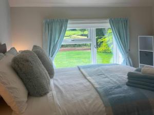 a bedroom with a bed with a large window at Fron-Haul in Llansantffraid-ym-Mechain