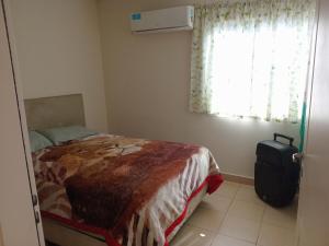 a bedroom with a bed and a suitcase next to a window at Coastal Apartment in Monte Caseros