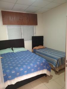 a bedroom with two beds and two windows at Coastal Apartment in Monte Caseros
