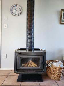 a stove in a room with a basket and a clock at Handy to Town, Spacious, Relaxed - KK14905 in Kaikoura