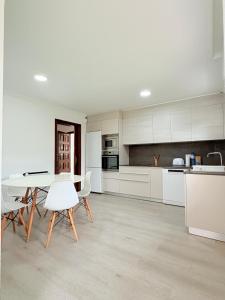 a kitchen with white cabinets and a table and chairs at Chalet independiente zona Coruxo in Oya