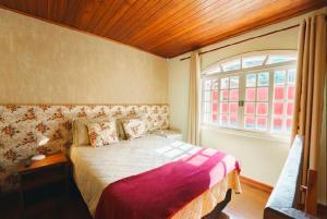 a bedroom with a large bed and a window at Suites CAMINHO DA FÉ in Campos do Jordão