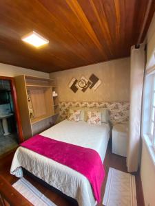 a bedroom with a large bed with a red blanket at Suites CAMINHO DA FÉ in Campos do Jordão +10 photos