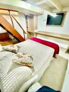 a bedroom with a bed with pillows and a television at Suites CAMINHO DA FÉ in Campos do Jordão