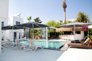 a pool with chairs and umbrellas next to a building at Sör Apart Otel in Bodrum City