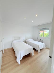two beds in a room with white walls and wooden floors at Chalet independiente zona Coruxo in Oya +41 photos