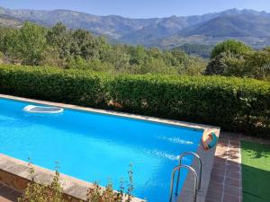a blue swimming pool with mountains in the background at Finca Bellavista de Gredos in Madrigal de la Vera