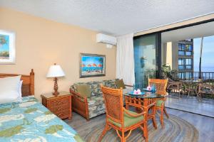 a hotel room with a bed and a table and chairs at Noelani 113 in Kahana