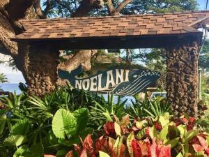 a sign in a garden with plants and flowers at Noelani 113 in Kahana