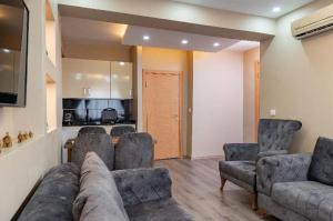 a living room with a couch and chairs and a kitchen at Saltanat Apartment in Istanbul