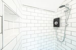 a white tiled shower with a shower head at The Snug - Cosy Annexe Hideaway in Portishead +21 photos