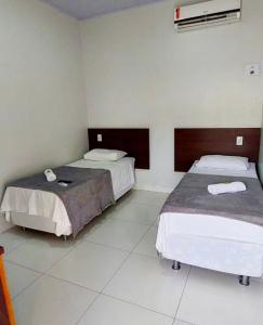 a bedroom with two beds and a air conditioner at Hotel Mirage in Alta Floresta +6 photos
