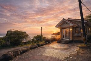 a small house with a sunset in the background at Villa Amoria Ocean View in Miyazaki