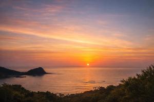 a sunset over the ocean with the sun in the sky at Villa Amoria Ocean View in Miyazaki