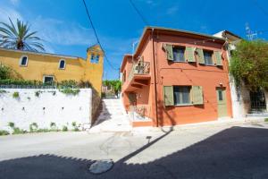an orange building with a white wall and a church at Kantouni Corfu in Potamós