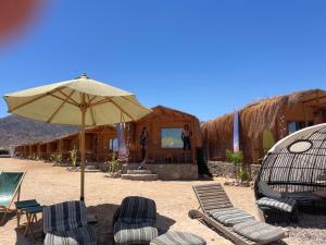 a group of chairs and an umbrella on a beach at Genena Eco-lodge in Nuweiba
