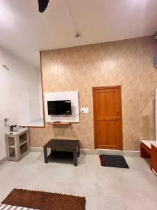 a living room with a tv and a wooden door at Ramaya Retreat Ayodhya in Faizābād