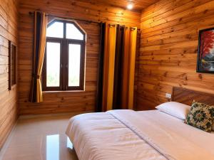 a bedroom with wooden walls and a bed with a window at The Yak House in Chakrāta