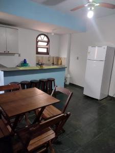 a kitchen with a wooden table and a refrigerator at Farol das Gaivotas Pousada e Residence in Caraguatatuba