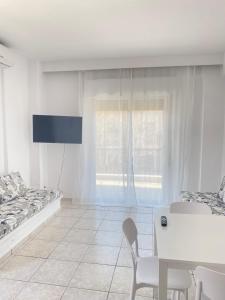 a white living room with a table and a tv at Ioli Beach in Skala Fourkas