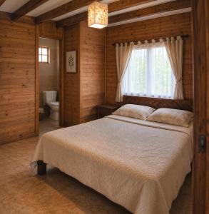a bedroom with a bed and a window and a toilet at Mirador Mindo in Mindo