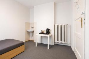 a room with a bed and a table and a radiator at Rooms Gdynia Orłowo in Gdynia