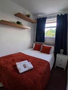 a bedroom with a bed with a red blanket and a window at Large river side house, parking,for 9 people in Bedford